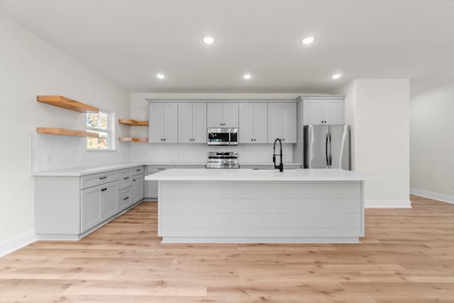 kitchen featuring decorative backsplash, light hardwood / wood-style floors, a center island, and appliances with stainless steel finishes