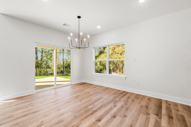 unfurnished dining area with a chandelier and light hardwood / wood-style flooring