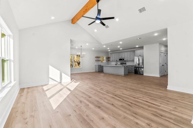 unfurnished living room featuring sink, high vaulted ceiling, light hardwood / wood-style floors, beamed ceiling, and ceiling fan with notable chandelier