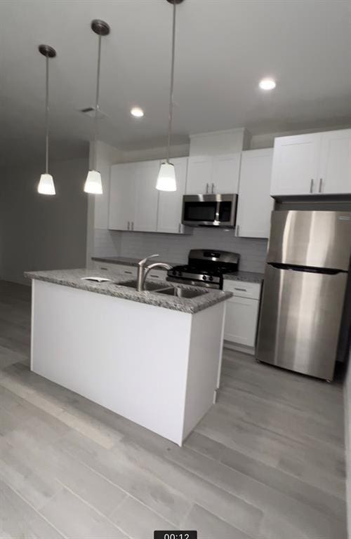 kitchen with white cabinetry, sink, decorative light fixtures, and appliances with stainless steel finishes