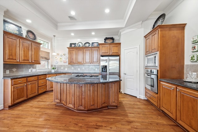 kitchen with sink, appliances with stainless steel finishes, dark stone countertops, a kitchen island, and a raised ceiling