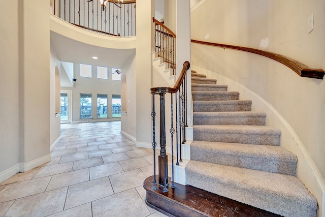 staircase with a towering ceiling and tile patterned flooring