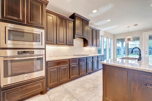 kitchen with dark brown cabinetry, appliances with stainless steel finishes, sink, and decorative backsplash