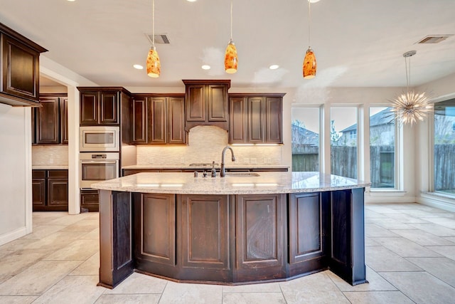 kitchen with sink, decorative light fixtures, dark brown cabinets, and stainless steel appliances