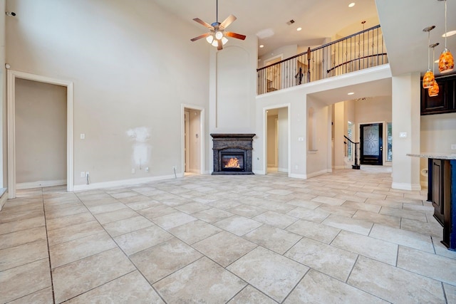 unfurnished living room with ceiling fan and a towering ceiling