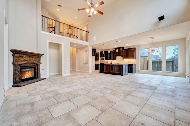 unfurnished living room with sink, ceiling fan, and a high ceiling