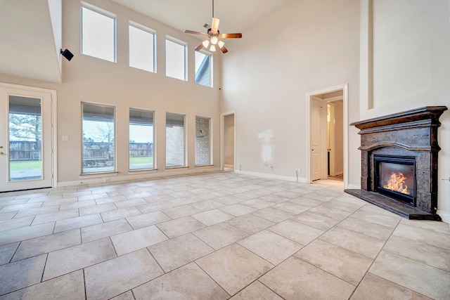 unfurnished living room with ceiling fan, a towering ceiling, and light tile patterned floors