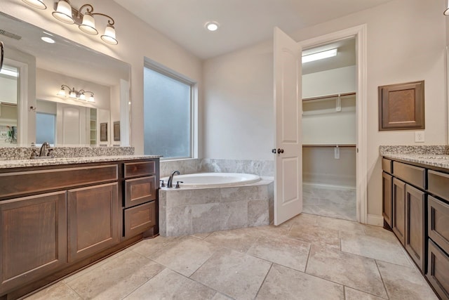 bathroom with a relaxing tiled tub and vanity