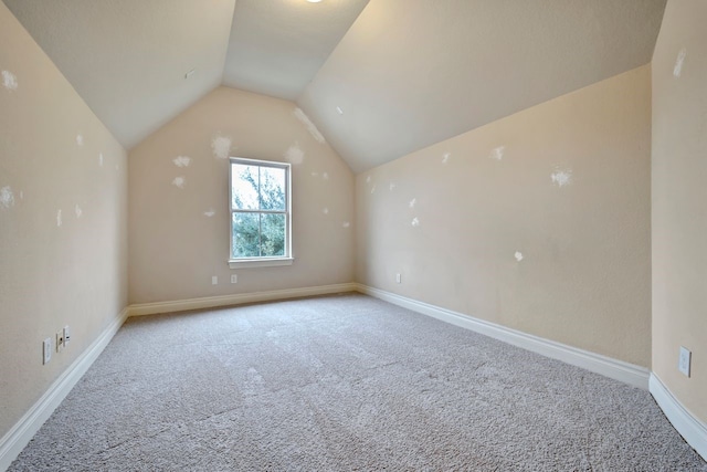 bonus room with light colored carpet and vaulted ceiling