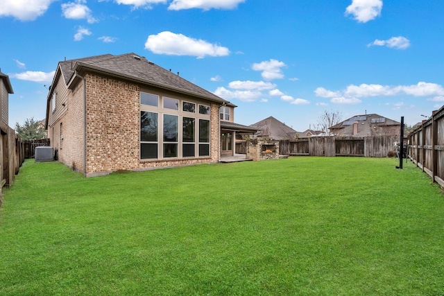 rear view of house with central AC and a lawn