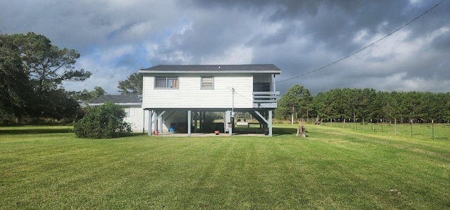 rear view of house featuring a wooden deck, a yard, and a patio