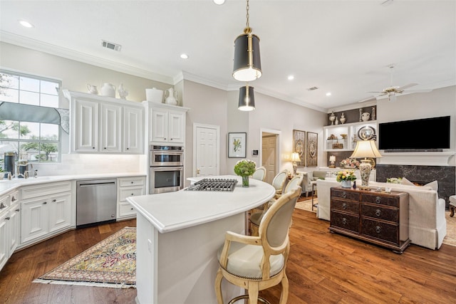 kitchen featuring stainless steel appliances, a breakfast bar area, white cabinets, and decorative light fixtures