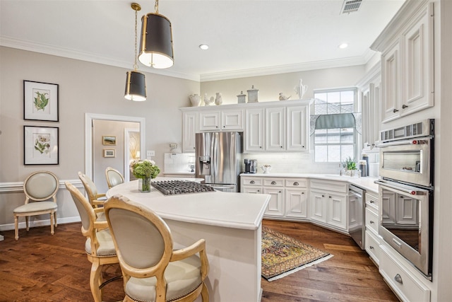 kitchen with white cabinetry, hanging light fixtures, dark hardwood / wood-style flooring, a kitchen island, and stainless steel appliances