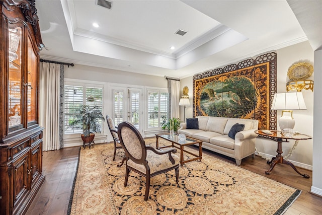 living room featuring dark hardwood / wood-style flooring, a tray ceiling, crown molding, and french doors