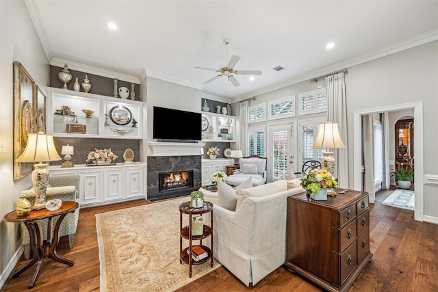 living room with ornamental molding, dark hardwood / wood-style floors, ceiling fan, and a high end fireplace