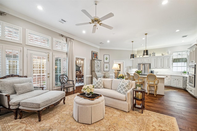 living room featuring ceiling fan, ornamental molding, and light wood-type flooring