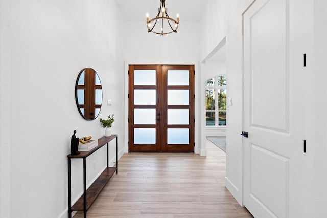 entrance foyer with french doors, light wood-type flooring, and a notable chandelier