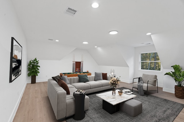 living room featuring lofted ceiling and light hardwood / wood-style floors