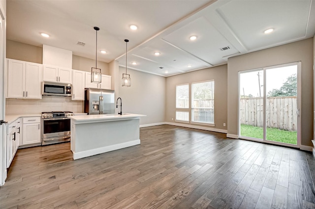 kitchen with a kitchen island, appliances with stainless steel finishes, decorative light fixtures, sink, and white cabinets