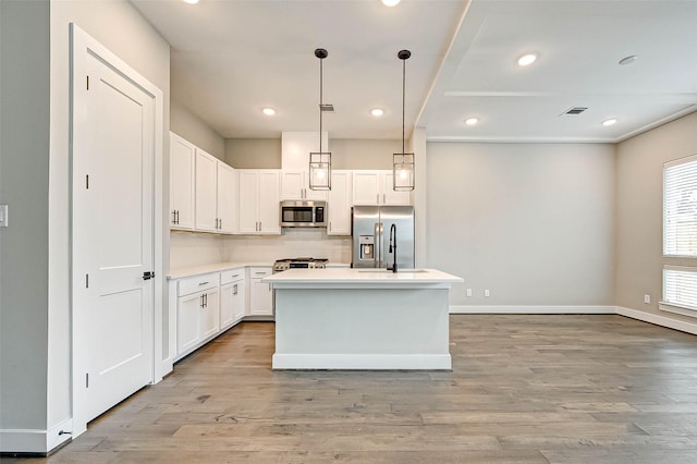 kitchen with decorative light fixtures, white cabinetry, a center island, stainless steel appliances, and light hardwood / wood-style flooring