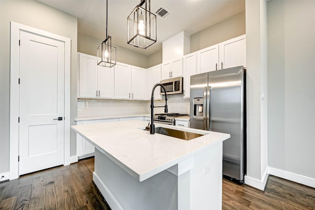 kitchen with dark wood-type flooring, white cabinetry, a center island with sink, pendant lighting, and stainless steel appliances