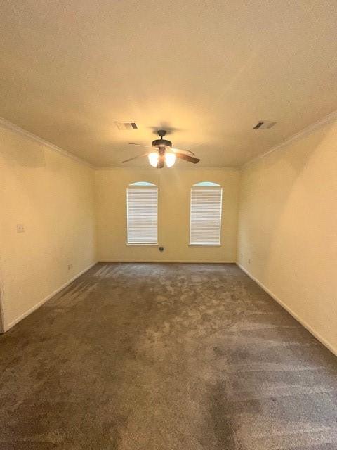 unfurnished room with dark carpet, crown molding, and ceiling fan