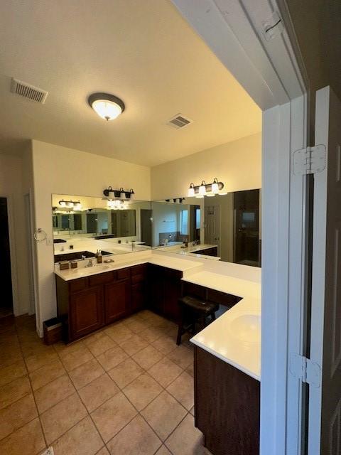 kitchen featuring dark brown cabinets, light tile patterned floors, and kitchen peninsula