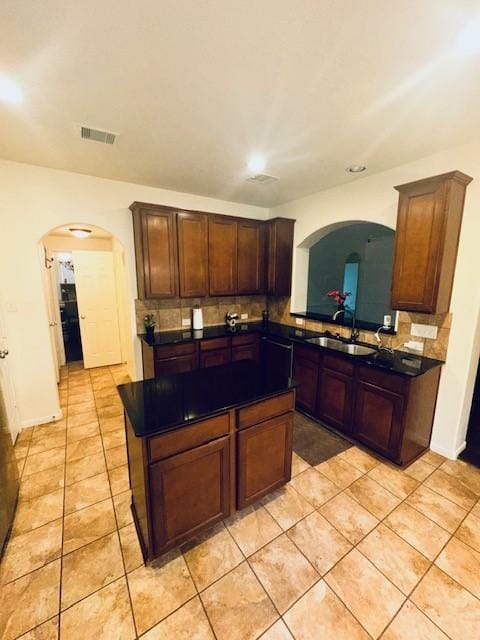 kitchen featuring dishwashing machine, sink, light tile patterned floors, tasteful backsplash, and a kitchen island