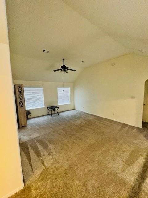 unfurnished living room featuring ceiling fan, vaulted ceiling, and carpet