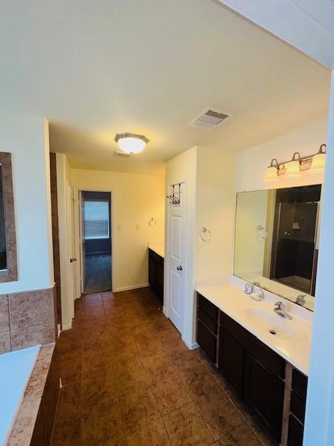 bathroom with tiled tub and vanity