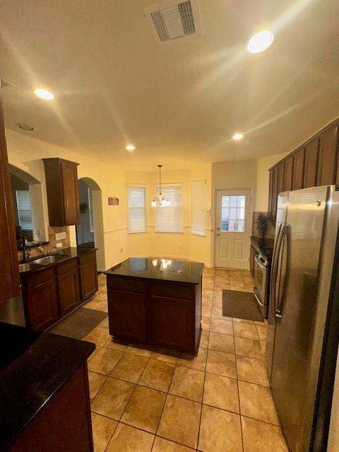 kitchen featuring pendant lighting, sink, appliances with stainless steel finishes, a kitchen island, and light tile patterned flooring