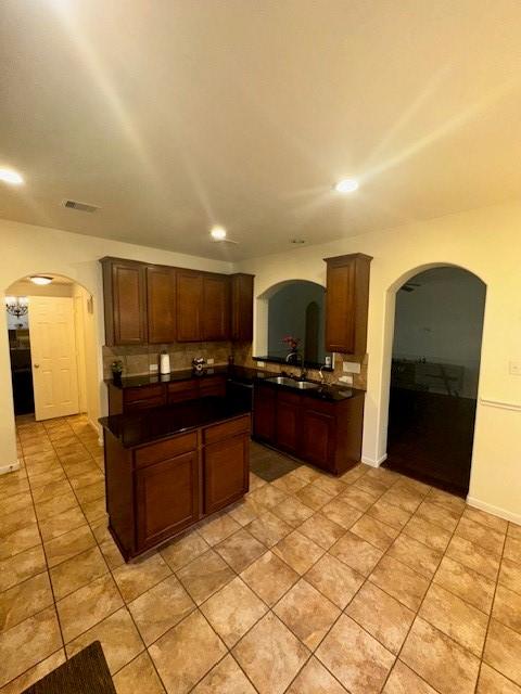 kitchen featuring sink, light tile patterned floors, dark brown cabinets, and a kitchen island