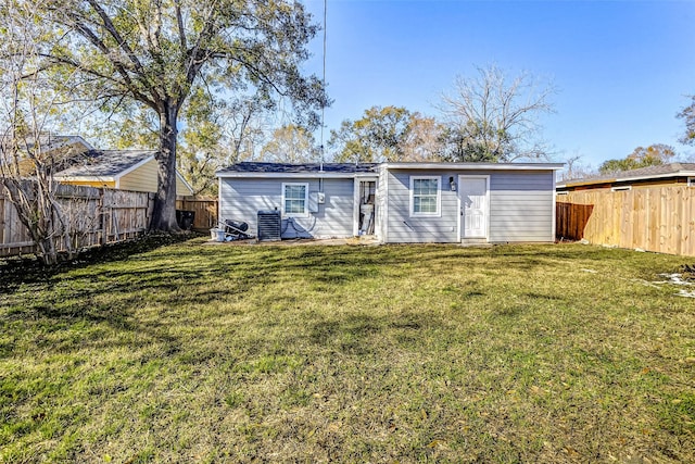 back of property with central AC, an outdoor structure, and a lawn