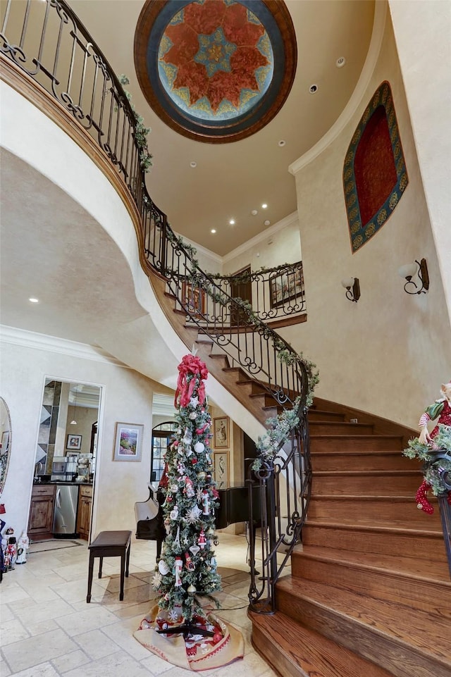 staircase featuring crown molding and a towering ceiling