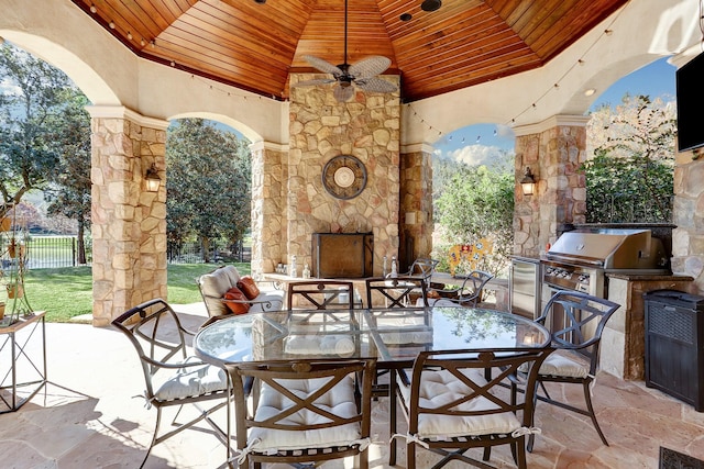 view of patio featuring an outdoor stone fireplace, an outdoor kitchen, area for grilling, and ceiling fan