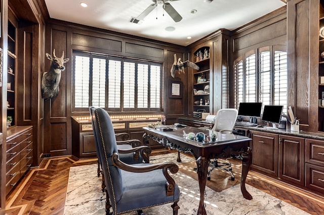 home office featuring ceiling fan, wooden walls, and dark parquet floors