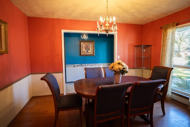 dining space featuring dark hardwood / wood-style flooring, a textured ceiling, and an inviting chandelier