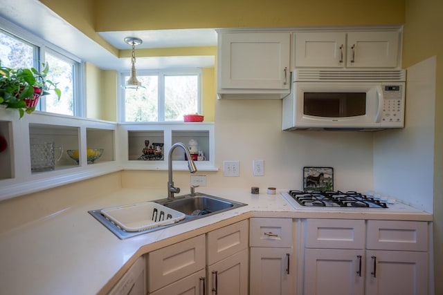 kitchen featuring white appliances, decorative light fixtures, sink, and white cabinets