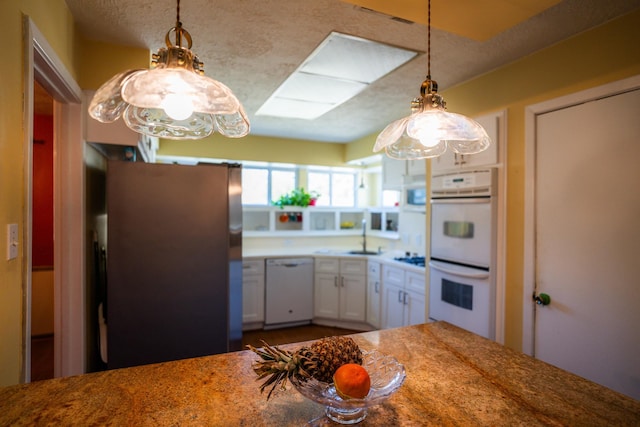 kitchen with white appliances, sink, hanging light fixtures, and white cabinets