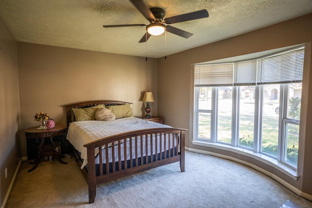 bedroom with ceiling fan, light colored carpet, and a textured ceiling