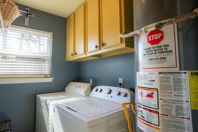 clothes washing area featuring cabinets, gas water heater, and washer and dryer