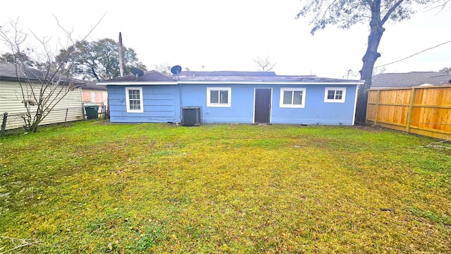 rear view of property with cooling unit and a lawn