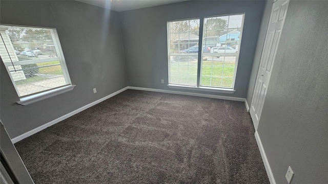 spare room with a healthy amount of sunlight and dark carpet