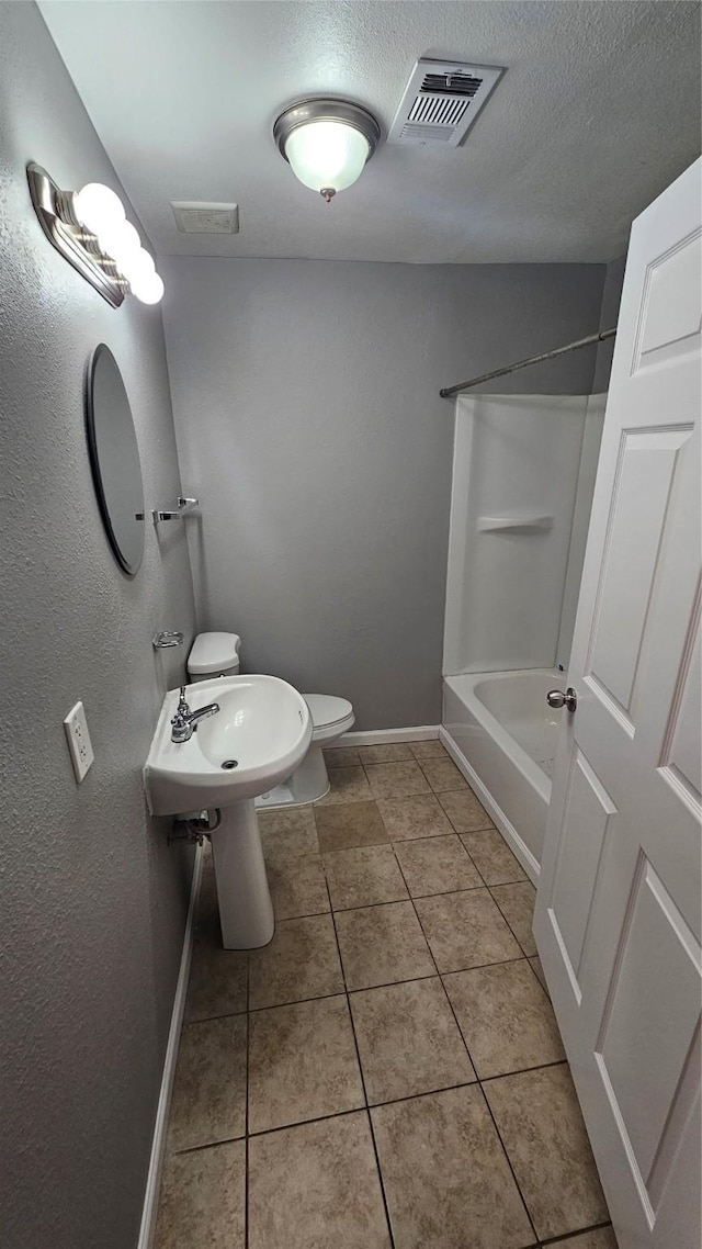 bathroom featuring tile patterned floors, toilet,  shower combination, and a textured ceiling