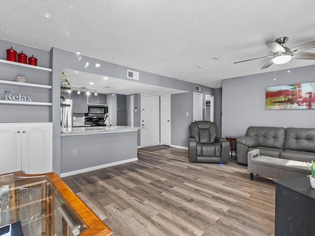 living room featuring ceiling fan, dark hardwood / wood-style flooring, and a textured ceiling