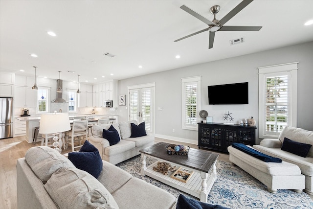 living room featuring plenty of natural light, ceiling fan, and light wood-type flooring