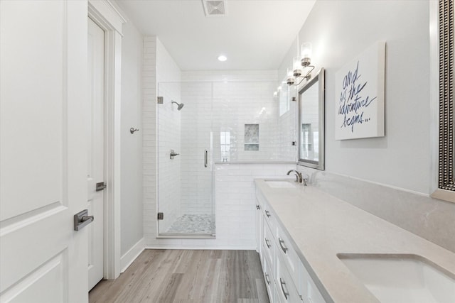 bathroom featuring wood-type flooring, a shower with door, and vanity