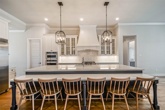 kitchen with stainless steel appliances, a large island, sink, and custom range hood