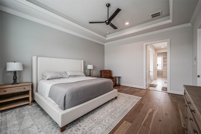 bedroom featuring hardwood / wood-style flooring, a raised ceiling, ceiling fan, and ensuite bathroom