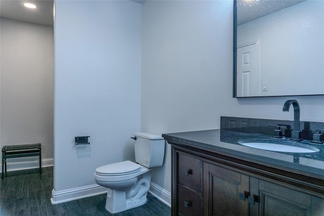 bathroom with vanity, toilet, and hardwood / wood-style floors